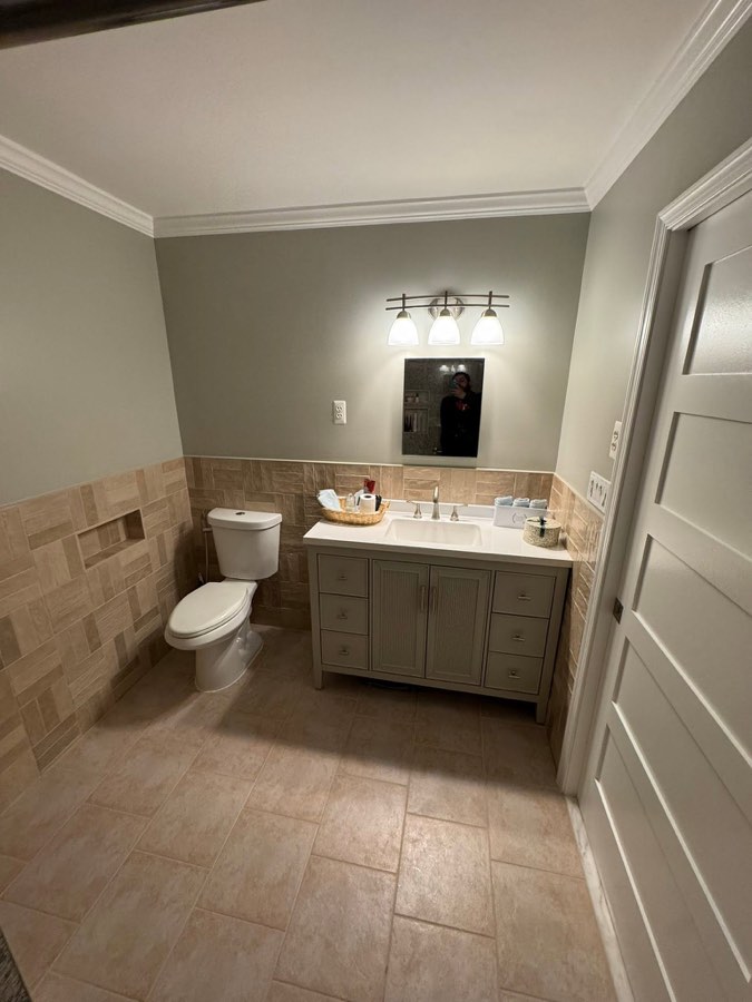 Guest bathroom with basketweave tile wainscot, new toilet, and gray vanity with quartz top
